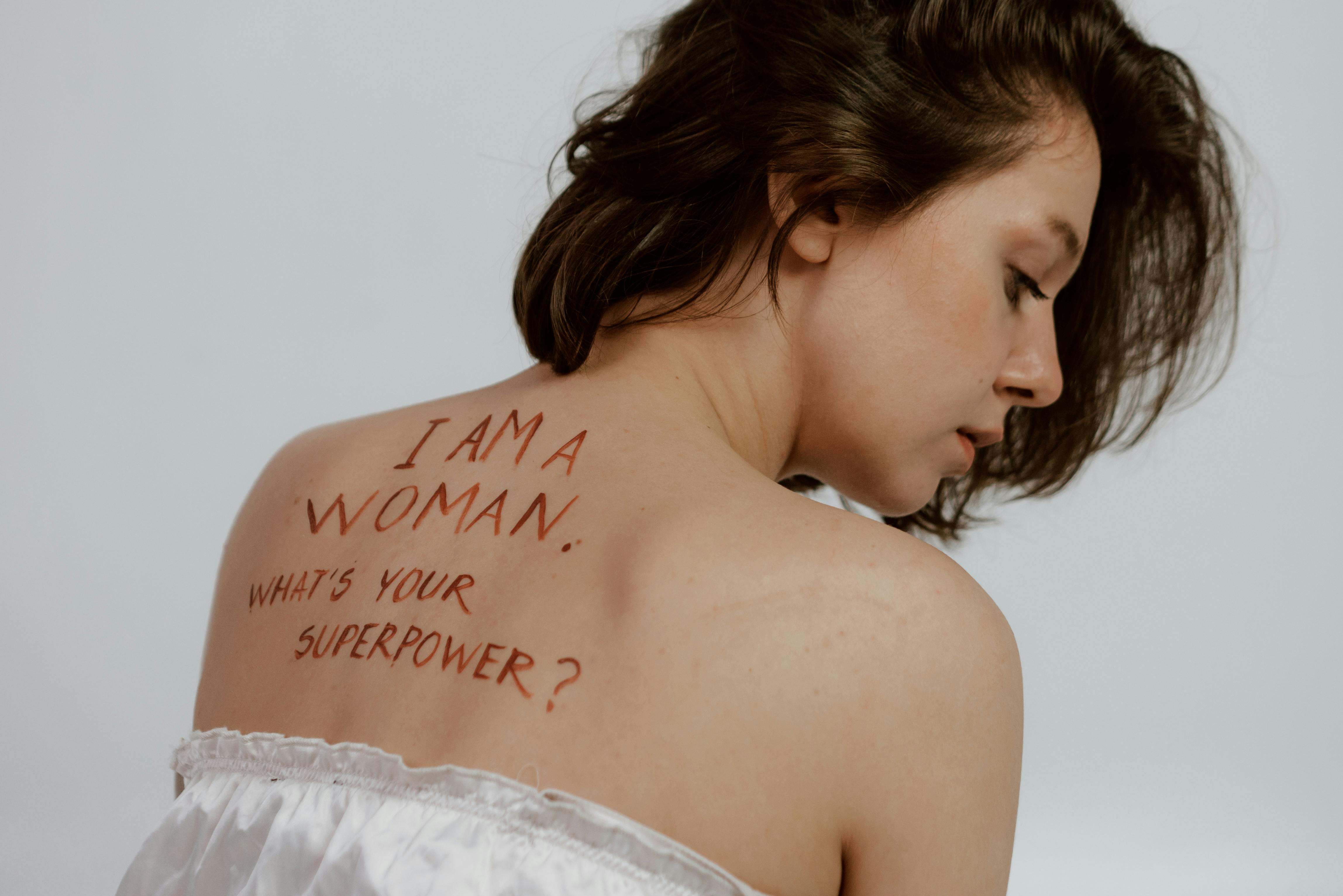 Woman with writIng on her bac that reads: "I am a woman. What is your superpower?"
